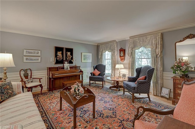 living area with a wainscoted wall, ornamental molding, a decorative wall, and wood finished floors