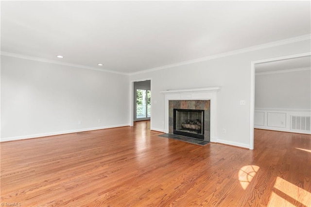 unfurnished living room featuring ornamental molding, a tile fireplace, visible vents, and wood finished floors