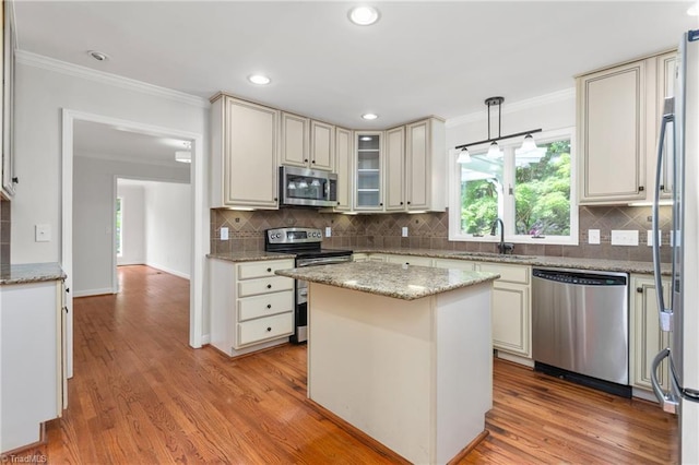 kitchen with crown molding, light wood finished floors, a sink, and appliances with stainless steel finishes
