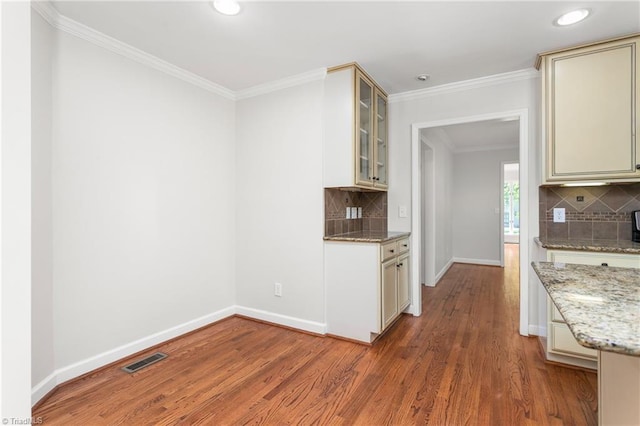 kitchen featuring baseboards, visible vents, wood finished floors, and decorative backsplash