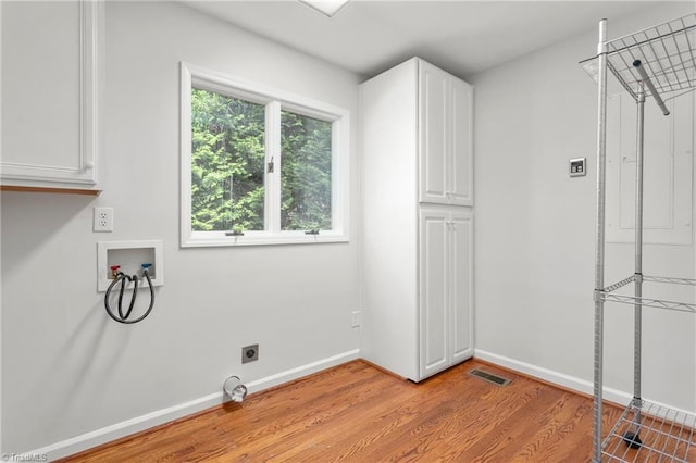 laundry room featuring washer hookup, electric dryer hookup, visible vents, light wood finished floors, and cabinet space