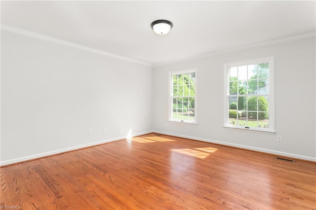 unfurnished room with visible vents, crown molding, light wood-style flooring, and baseboards
