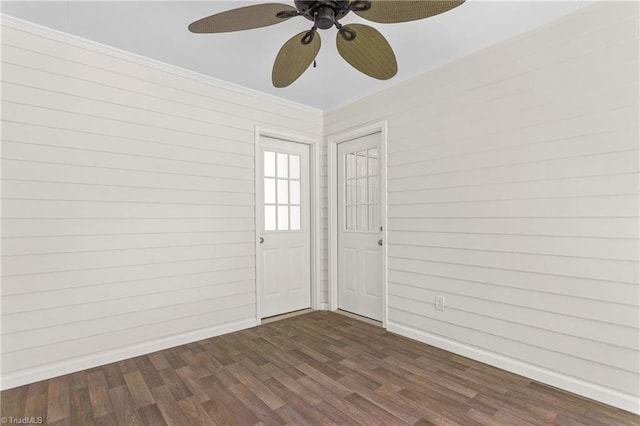 empty room with ornamental molding, a ceiling fan, dark wood-style flooring, and baseboards
