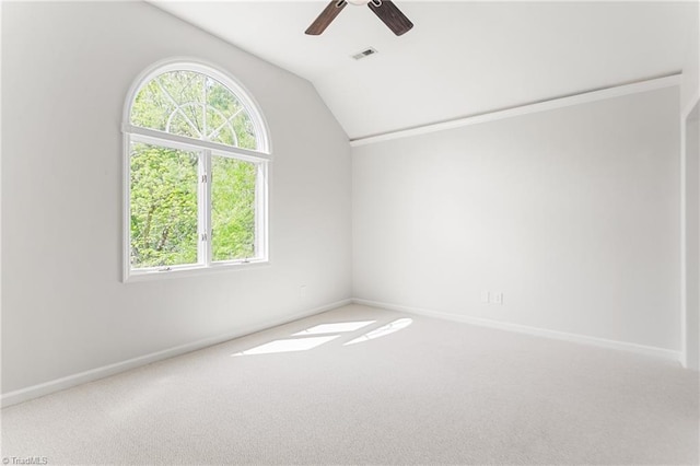 carpeted spare room featuring lofted ceiling, visible vents, a healthy amount of sunlight, and a ceiling fan