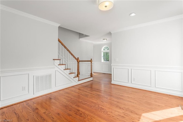 spare room with crown molding, stairs, visible vents, and a decorative wall