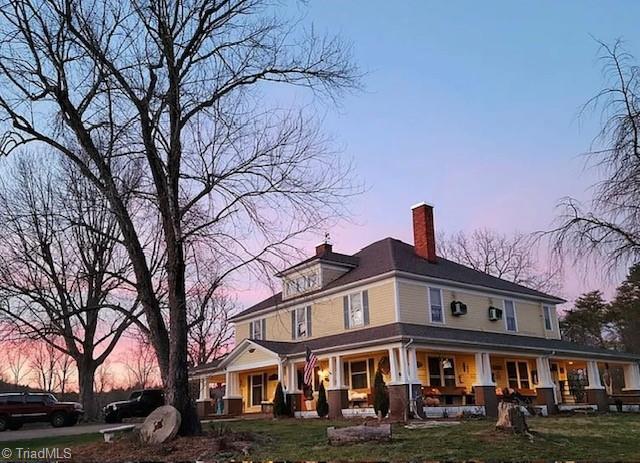 1715 Alfred Hartley Rd, Lenoir, NC 28645 - back of house at dusk with a porch, a chimney, and a yard