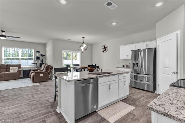 kitchen featuring a wealth of natural light, a center island with sink, appliances with stainless steel finishes, and white cabinetry