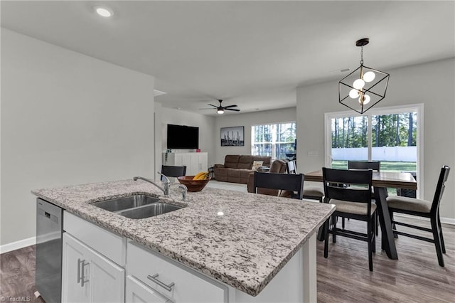 kitchen featuring hardwood / wood-style flooring, sink, white cabinets, hanging light fixtures, and a center island with sink