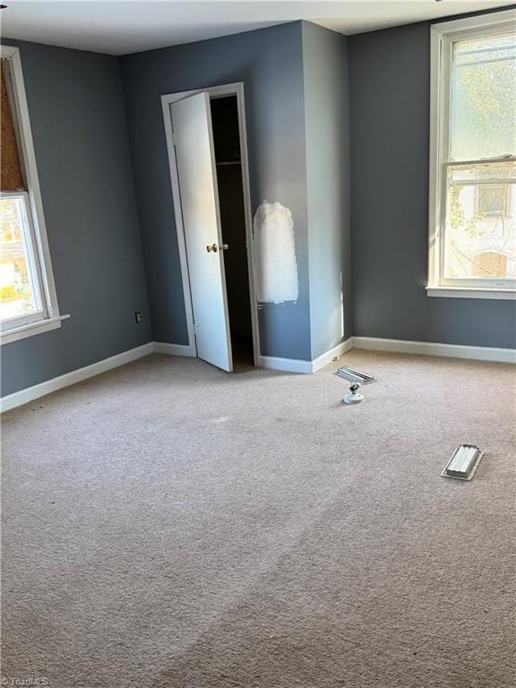 unfurnished bedroom featuring multiple windows and light colored carpet