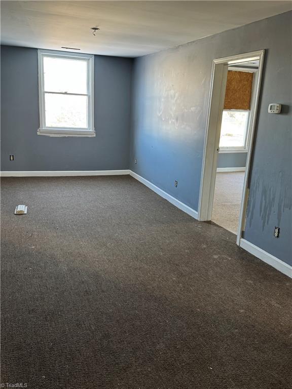 spare room with dark carpet