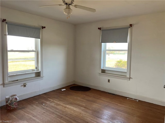 unfurnished room with baseboards, visible vents, wood finished floors, and ceiling fan