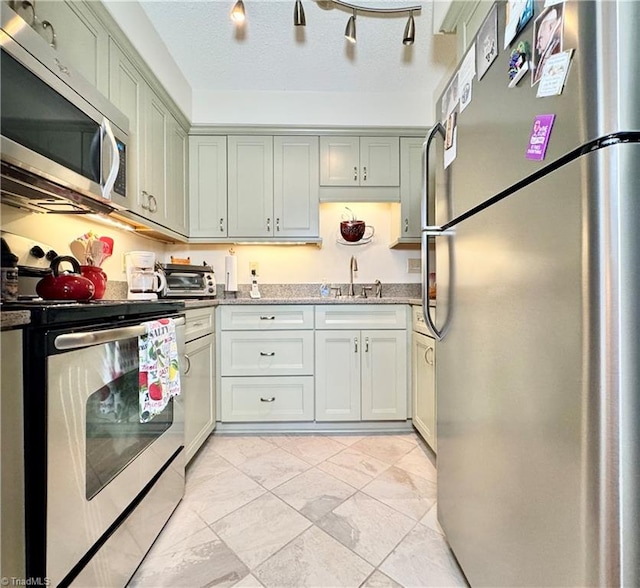 kitchen featuring a textured ceiling, sink, light stone countertops, and stainless steel appliances