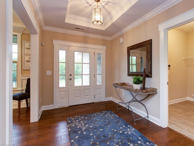 doorway with dark hardwood / wood-style floors, a raised ceiling, and ornamental molding