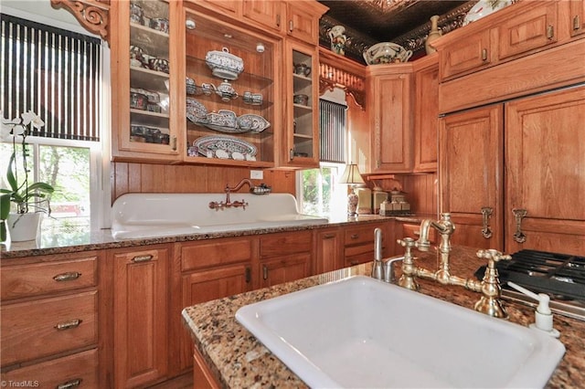 kitchen featuring sink, paneled built in refrigerator, and light stone counters