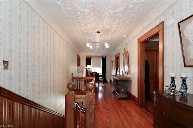 hallway featuring a chandelier, crown molding, and hardwood / wood-style floors