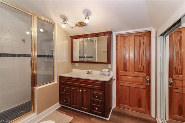 bathroom with lofted ceiling, hardwood / wood-style floors, vanity, and an enclosed shower