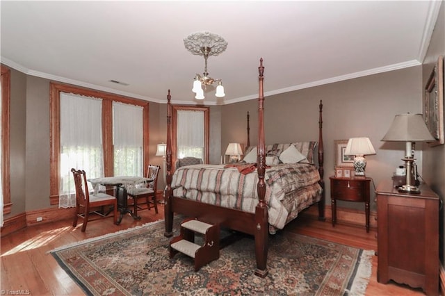 bedroom featuring hardwood / wood-style floors, a notable chandelier, and ornamental molding