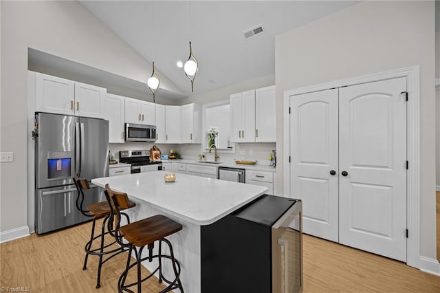 4944 Little Store Rd, Mcleansville, NC 27301 - kitchen with appliances with stainless steel finishes, a kitchen breakfast bar, light wood-style floors, a kitchen island, and high vaulted ceiling