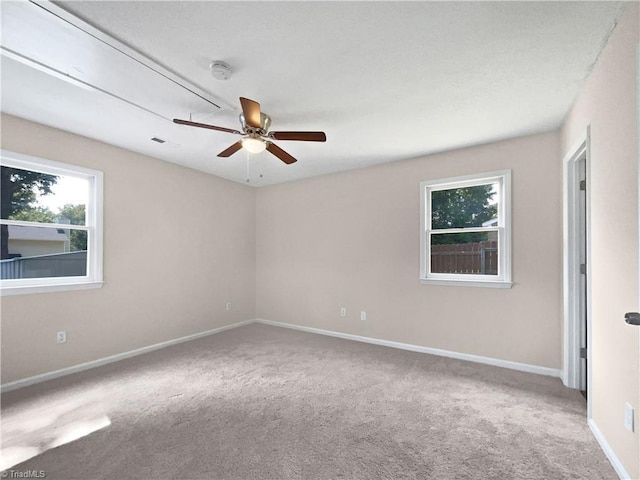 carpeted empty room with ceiling fan and baseboards