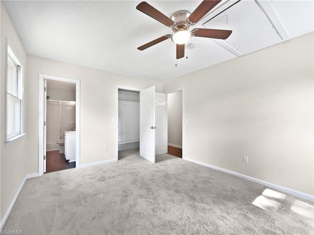 unfurnished bedroom featuring attic access, baseboards, a ceiling fan, ensuite bath, and carpet flooring