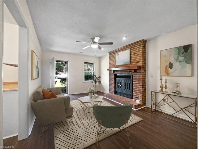 living area with a fireplace, a textured ceiling, baseboards, and wood finished floors