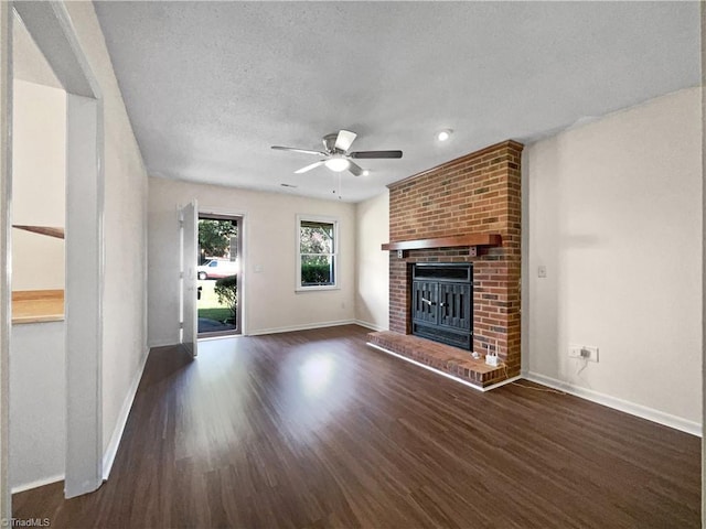 unfurnished living room featuring baseboards, dark wood finished floors, a ceiling fan, a textured ceiling, and a fireplace