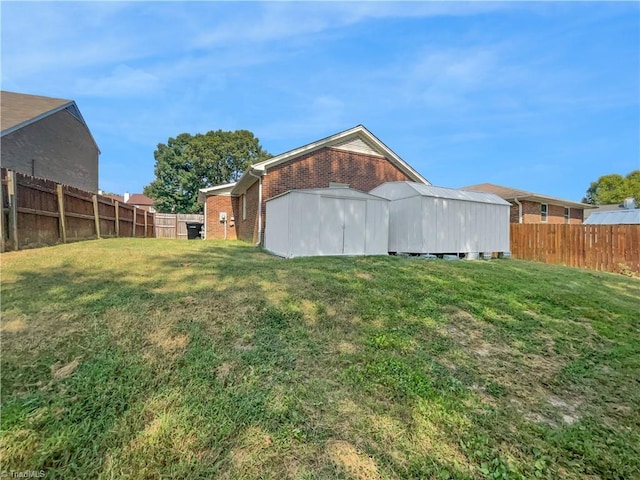 rear view of property with brick siding, a lawn, and a fenced backyard