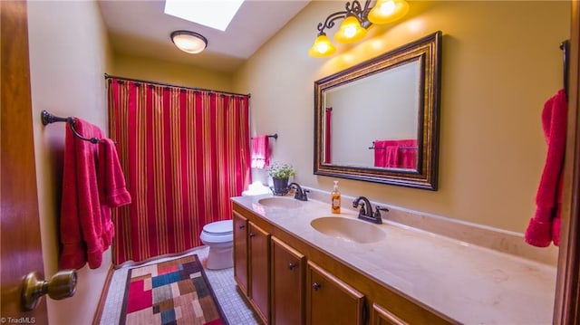 bathroom with a skylight, double vanity, toilet, and a shower with curtain