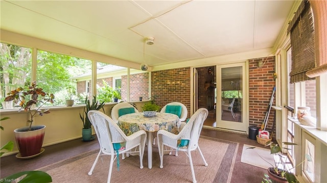 sunroom / solarium featuring brick wall and outdoor dining area