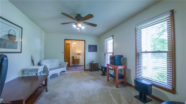 living area featuring a ceiling fan, carpet, and baseboards