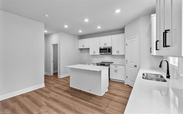4192 Emmas Way E, Bend, NC 27018 - kitchen with appliances with stainless steel finishes, a sink, a center island, recessed lighting, and white cabinetry