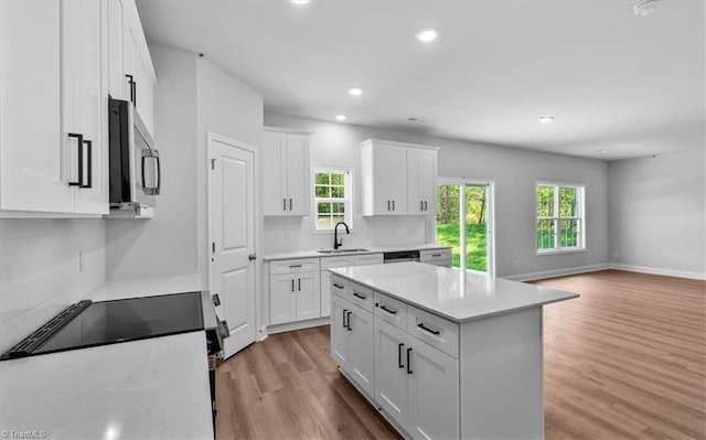 4192 Emmas Way E, Bend, NC 27018 - kitchen featuring appliances with stainless steel finishes, a sink, tasteful backsplash, white cabinetry, and light wood-style floors