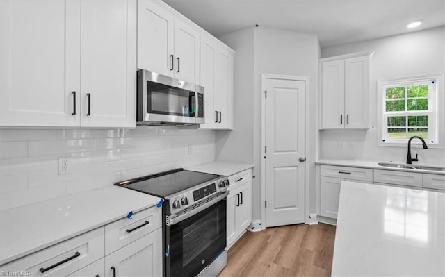 4192 Emmas Way E, Bend, NC 27018 - kitchen featuring appliances with stainless steel finishes, a sink, white cabinets, light wood-style floors, and recessed lighting