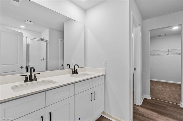 4192 Emmas Way E, Bend, NC 27018 - full bathroom featuring a stall shower, double vanity, a spacious closet, baseboards, and wood finished floors
