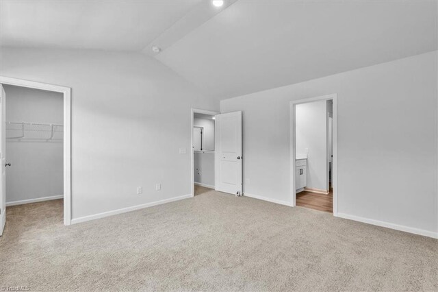 4192 Emmas Way E, Bend, NC 27018 - unfurnished bedroom featuring vaulted ceiling, carpet, a walk in closet, baseboards, and ensuite bathroom