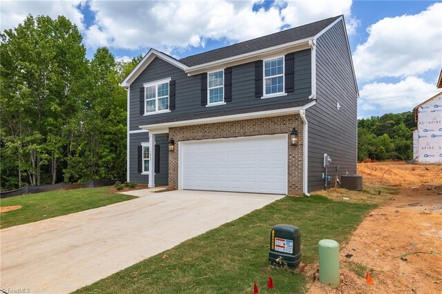 4192 Emmas Way E, Bend, NC 27018 - view of front facade featuring an attached garage, concrete driveway, brick siding, central AC unit, and a front yard