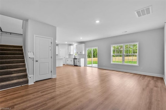 4192 Emmas Way E, Bend, NC 27018 - unfurnished living room with wood finished floors, recessed lighting, baseboards, and stairway
