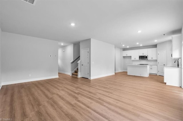 4192 Emmas Way E, Bend, NC 27018 - unfurnished living room with recessed lighting, light wood-style floors, stairs, and baseboards