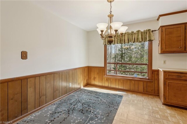 401 Joyce Rd, Hillsborough, NC 27278 - unfurnished dining area featuring an inviting chandelier, a wainscoted wall, wood walls, and light floors