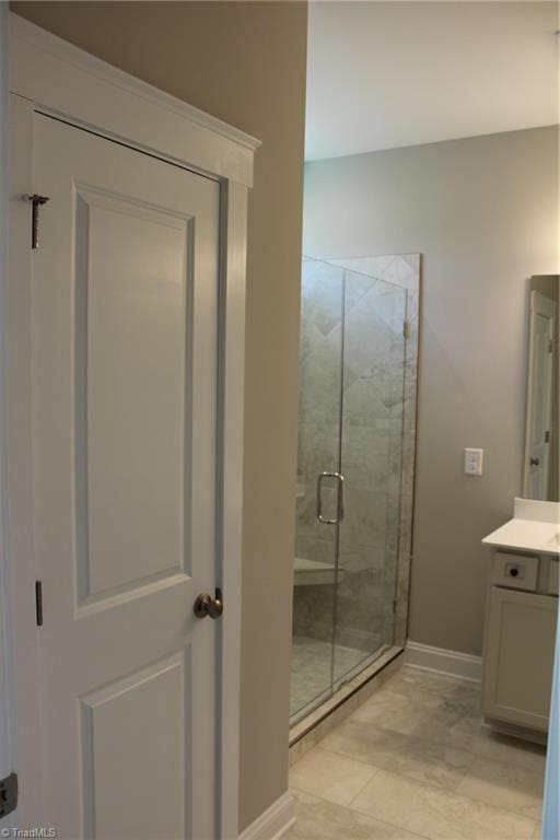 bathroom with a stall shower, vanity, and baseboards