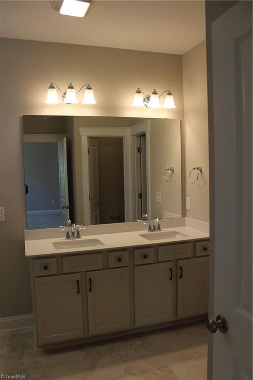 full bathroom with a sink, baseboards, and double vanity