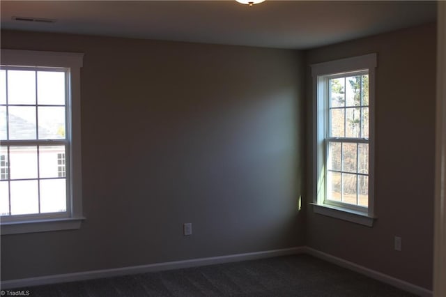 unfurnished room with visible vents, baseboards, and dark colored carpet