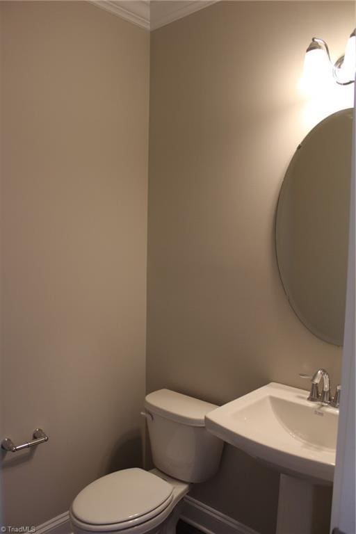 bathroom featuring toilet, baseboards, a sink, and ornamental molding