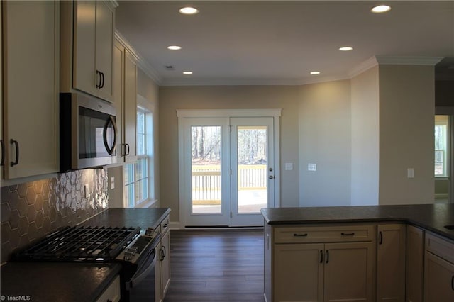 kitchen featuring ornamental molding, dark countertops, stainless steel microwave, and gas range