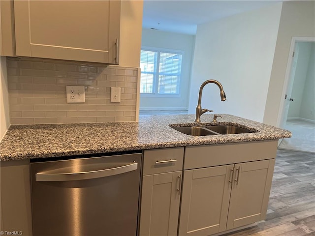 kitchen with stainless steel dishwasher, light hardwood / wood-style floors, sink, and stone counters