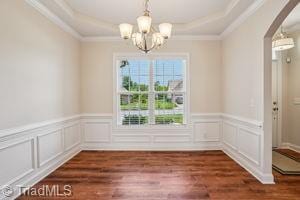 2834 Fallin Ct, High Point, NC 27262 - unfurnished dining area with a chandelier, arched walkways, a raised ceiling, crown molding, and wainscoting