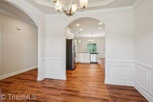2834 Fallin Ct, High Point, NC 27262 - unfurnished dining area with a chandelier, arched walkways, a decorative wall, wood finished floors, and crown molding