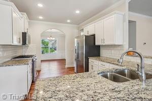 2834 Fallin Ct, High Point, NC 27262 - kitchen with crown molding, stainless steel appliances, light stone counters, white cabinetry, and dark wood-style floors
