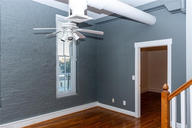 spare room with brick wall, wood-type flooring, and ceiling fan