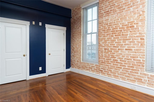 empty room featuring hardwood / wood-style floors and brick wall